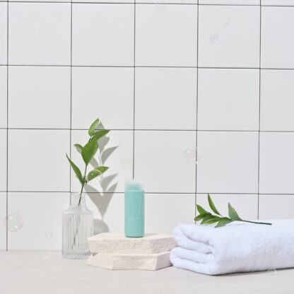 Cleanser are on two rocks between leaves inside bottle and one on towel